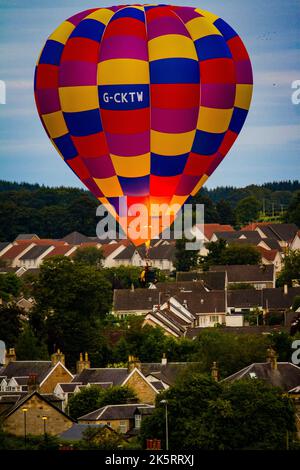 Eine vertikale Aufnahme eines farbenfrohen Heißluftballons, der während des Strathaven Ballonfestivals über dem Strathaven schwebt Stockfoto