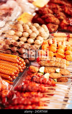 Straßenfleischhändler. Ein Marktstand mit einer Vielzahl von Fleischsnacks auf einem Stock - Thailand. Stockfoto