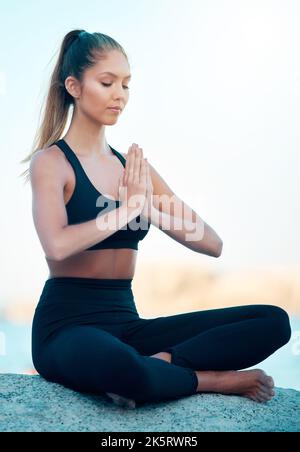 Schöne Frau meditiert während sie Yoga am Strand praktiziert. Junge Zen-Athletinnen trainieren draußen. Innere Ruhe finden, Gleichgewicht und Stockfoto
