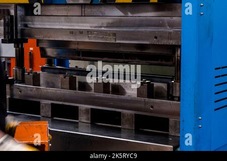 Hydraulische Abkantpresse oder Biegemaschine für Flachblech. Arbeiter biegen Blech auf Biegemaschine. Stockfoto