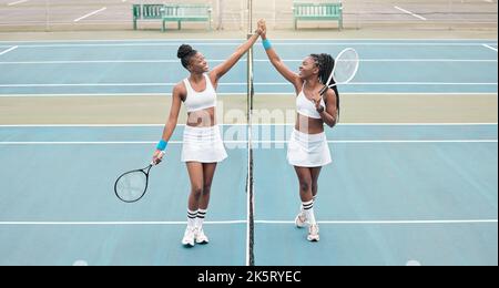 Junge Mädchen feiern nach einem Tennismatch. Profisportler motivieren sich gegenseitig mit einem High Five. afroamerikanische Spieler unterstützen sich gegenseitig Stockfoto