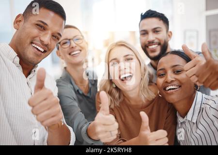 Porträt einer Gruppe selbstbewusster, diverser Geschäftsleute, die Daumen nach oben gestikulieren und gemeinsam in einem Büro Selfies machen. Fröhliche Kollegen, die lächeln Stockfoto