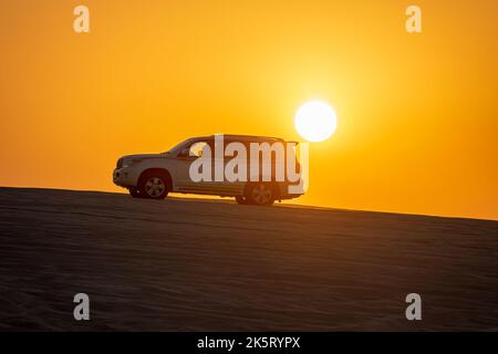 Toyota Landcruiser 4WD Fahrt durch Dünen bei Sonnenuntergang Zeit. Düne Bashing als Teil einer Wüstensafari in Katar Stockfoto