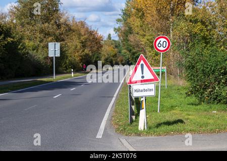 Ein Warnschild mit dem zusätzlichen Schild in deutscher Sprache , Mäharbeiten , am Straßenrand Stockfoto