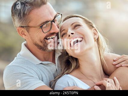 Glückliches und liebevolles reifes kaukasisches Paar, das an einem sonnigen Tag gemeinsam am Strand ein romantisches Date genießt. Fröhlicher, liebevoller Mann, der sich am Arm umarmte Stockfoto