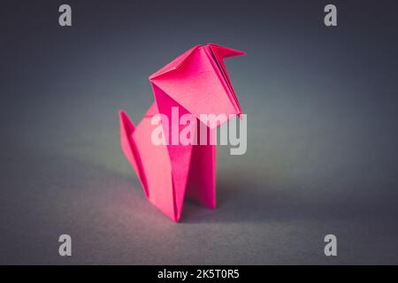 Rosa Papier Hund Origami isoliert auf einem weißen grauen Hintergrund. Stockfoto