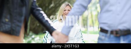 Paar hält Hände im Hintergrund lächelnde Frau im Rollstuhl Stockfoto