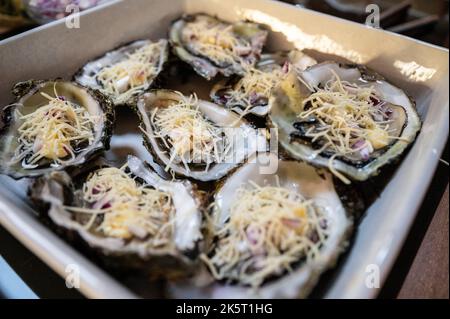 Frische Austern mit geriebenem Käse und Zwiebelvinaigrette, die im Ofen gebacken werden können Stockfoto