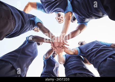 Unter verschiedenen Gruppen von Rugby-Spielern, die draußen auf einem Feld in einer Gruppe zusammenstehen. Junge männliche Athleten, die ernst und konzentriert aussehen, während sie zusammengekauert sind Stockfoto