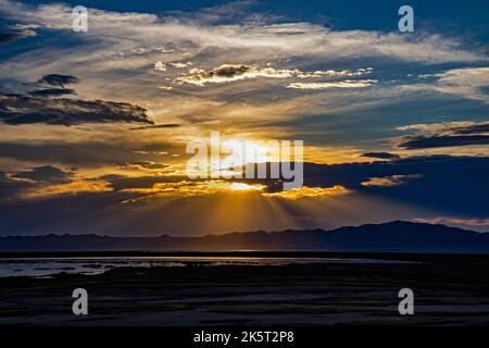 Die Strahlen der untergehenden Sonne scheinen über dem Antelope Island State Park vom Farmington Bay Waterfowl Management Area, Utah, USA, aus zu sehen. Stockfoto