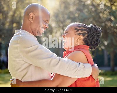 Glückliches, liebevolles, reifes afroamerikanisches Paar, das im Sommer einen intimen Moment im Park teilt. Verliebt lächelnde und umarmende Senioren Stockfoto