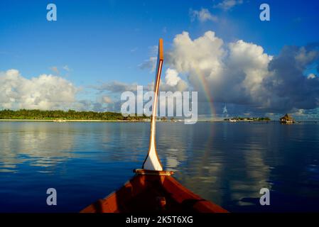 Ein wunderschöner Regenbogen über einer Wolkenlandschaft, aufgenommen von einem Boot, das auf ruhigen Meereswellen schwimmt Stockfoto