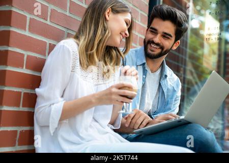 Glückliche junge Geschäftsleute, die im Freien chatten und digitale Geräte nutzen Stockfoto