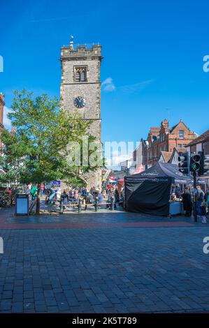 Am Samstagmarkttag sind Leute unterwegs, einige machen eine Pause unter dem Uhrenturm. St Albans, Hertfordshire, England, Großbritannien Stockfoto