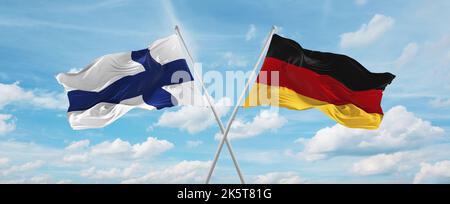 Zwei gekreuzte Flaggen Bundesrepublik Deutschland und finnland winken im Wind bei bewölktem Himmel. Konzept der Beziehung, Dialog, Reisen zwischen zwei Gräfin Stockfoto