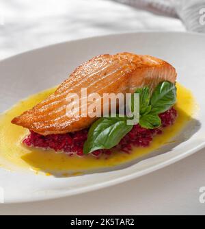 Lachssteak mit rotem Risotto auf weißem Hintergrund für die Speisekarte des Restaurants. Stockfoto