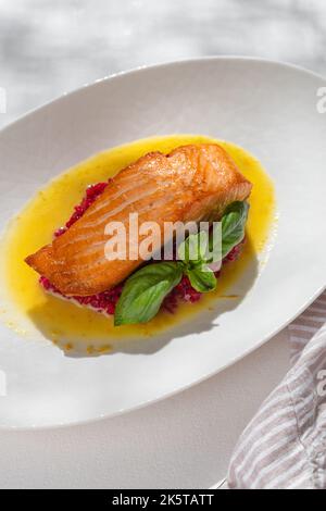 Lachssteak mit rotem Risotto auf weißem Hintergrund für die Speisekarte des Restaurants. Stockfoto