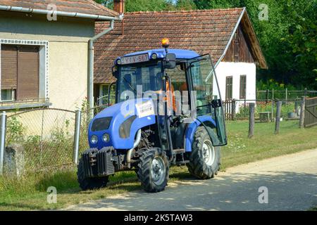 Kleiner kommunaler Traktor im Besitz der lokalen Behörden, der zum Schneiden von Grasrändern in der ländlichen Gasse des kleinen Weilers zala County ungarn verwendet wird Stockfoto