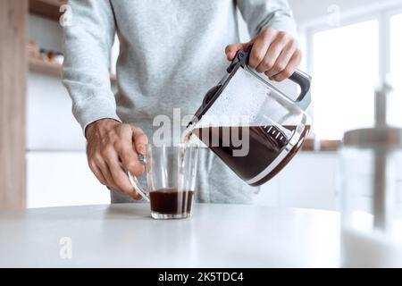 Der Mensch schenkt sich eine Tasse Kaffee Stockfoto