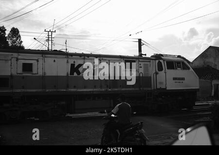 Cicalengka, West Java, Indonesien - 09. Oktober, 2022 : Eisenbahnüberfahrt, Monochromes Foto am Bahnübergang, wo mehrere Personen auf den Zug warten Stockfoto