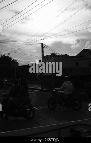 Cicalengka, West Java, Indonesien - 09. Oktober, 2022 : Eisenbahnüberfahrt, Monochromes Foto am Bahnübergang, wo mehrere Personen auf den Zug warten Stockfoto