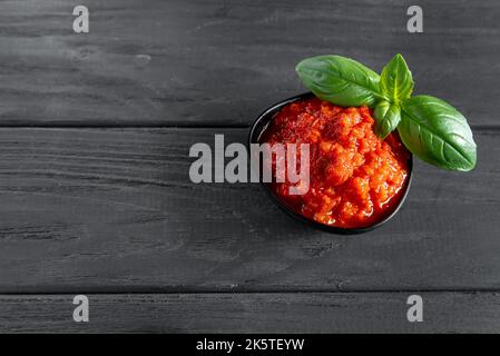 Gemüsepaste, auf einem dunklen Holzhintergrund in einem schwarzen Basilikumblätterkuchen. Vegetarismus und gesunde Ernährung. Draufsicht und Kopierbereich. Stockfoto