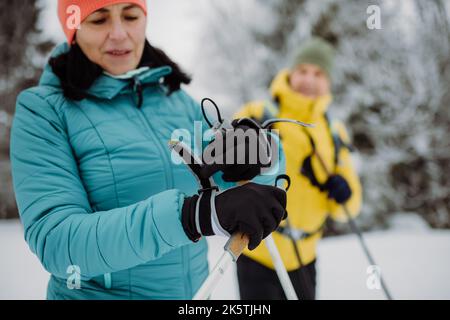 Ältere Frau, die mit ihrem Mann Ski-Handschuhe anlegt, während des Skilanglaufs. Stockfoto