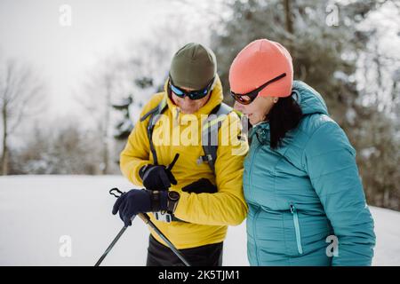 Seniorenpaar beim Skifahren auf der Smartwatch. Stockfoto
