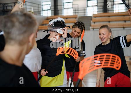 Gruppe von jungen und alten fröhlichen Frauen, Unihockey-Team-Spieler, in der Turnhalle abtretenden Sieg. Stockfoto