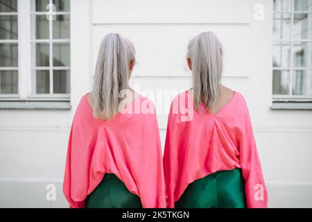 Ältere Frauen Zwillinge in bunten Kleidern in der Stadt, Einkaufen.Rückansicht. Stockfoto