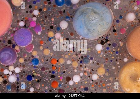 Acrylfarbe Kugeln abstrakte Textur. Leuchtende Farben fließendes Tapetendesign. Violette, blaue, rosa und gelbe Flüssigkeiten mischen sich. Stockfoto