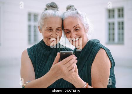 Ältere Frauen Zwillinge im Freien in der Stadt überprüfen Smartphone. Stockfoto