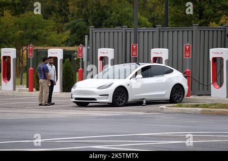 Genua, Ohio, USA. Ein Tesla-Auto, das an einer Tesla-Ladestation für Elektrofahrzeuge an einer Raststelle entlang der Ohio Turnpike oder der Ohio toll Road aufgeladen wird. Stockfoto