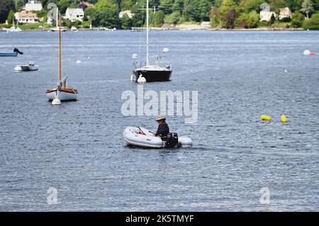 Portsmouth, New Hampshire, USA. Mann steuert ein Schlauchboot unter den Segelbooten und anderen Schiffen, die Portsmouth Harbour säumen. Stockfoto