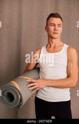 Ein Mann hält eine Yogamatte in den Händen Stockfoto