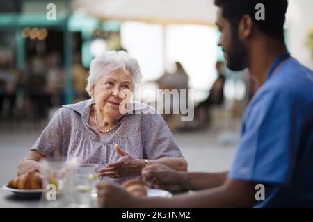 Pfleger beim Frühstück mit seinem Kunden im Café. Stockfoto