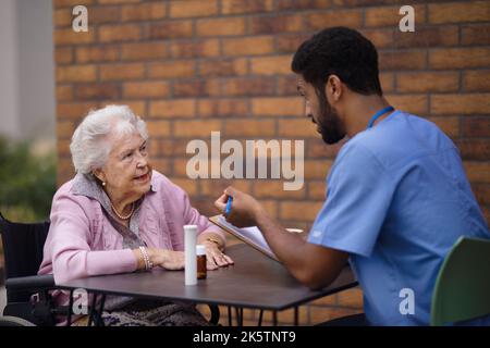 Pfleger erklärt Einnahme von Pillen zu älteren Frau. Stockfoto