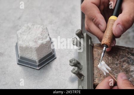 Zahntechniker Zahnarzt Mann mit Zahnersatz in seinem Labor mit Wachs, Nahaufnahme. Zahntechniker modelliert Zahnkronen mit heißem Wachs. Stockfoto