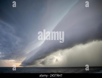 Adria, Italien. 01. Oktober 2022. Ein US Navy F/A-18E Super Hornet Kampfflugzeug, das Carrier Air Wing 7 zugewiesen wurde, fliegt vor einer Wand aus Wolken und Regen, als es sich nähert, auf dem Flugdeck des Nimitz-Klasse Flugzeugträgers USS George H.W. zu landen Bush in der Adria, 1. Oktober 2022 vor der italienischen Küste. Stockfoto