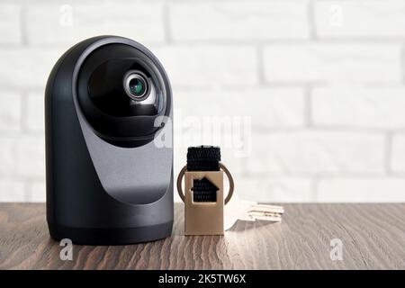 IP-Kamera und herkömmliche Türschlüssel auf dem Tisch. Wireless Home Protection und Sicherheitskontrollkonzept. CCTV Stockfoto