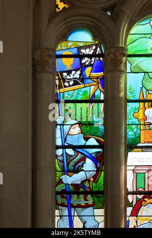 Ein Ritter, der ein Banner mit seinem Wappen auf einem Buntglasfenster in der Basilika von Bois-Chenu in Domrémy-la-Pucelle (Vogesen), Frankreich, hält Stockfoto