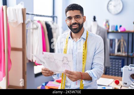 Junger arabischer Mann, Schneider, lächelnd, selbstbewusstes Kleidungsdesign im Schneider-Shop Stockfoto
