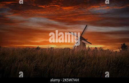 Alte Windmühlen in Kinderdijk bei dramatischem Sonnenuntergang in den Niederlanden Stockfoto