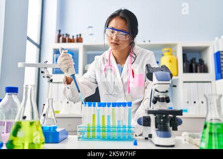 Junge chinesische Frau in Wissenschaftleruniform, die im Labor arbeitet Stockfoto