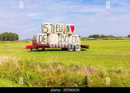 Unterstützen Sie die Farmer-Briefe auf Heuballen auf dem Anhänger auf der Wiese in Heiloo, Niederlande. Stockfoto