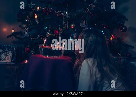 Mädchen beobachten Tradition weihnachten schwimmende Nüsse mit brennenden Kerzen auf weihnachten Bokeh glühenden Hintergrund Stockfoto