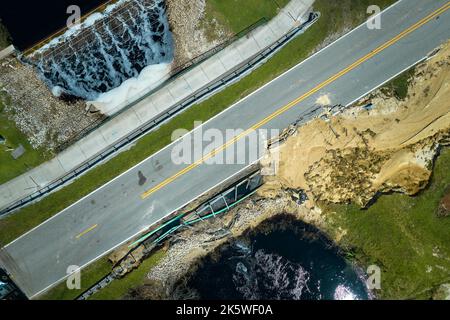 Luftaufnahme der beschädigten Straßenbrücke über den Fluss, nachdem das Hochwasser den Asphalt weggespült hatte. Wiederaufbau der zerstörten Verkehrsinfrastruktur. Stockfoto