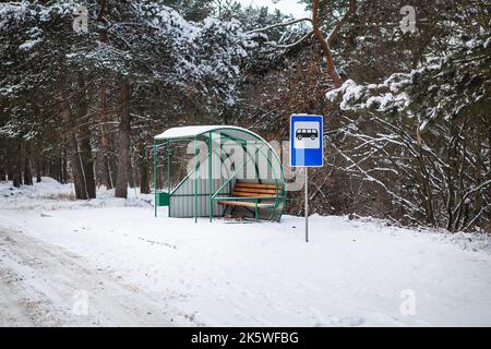 Bushaltestelle in der Mitte einer schönen Winterstraße Mitten im Wald mit Bushaltestelle zeichen Stockfoto