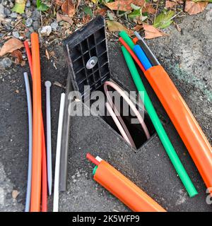 Glasfaser-Breitbandanschluss verwarf zufällige Kabelresten neben offener Anschlussdose für Verbraucher zur Illustration und angeschlossenes Kundenkabel bereit, falls gewünscht in Großbritannien Stockfoto