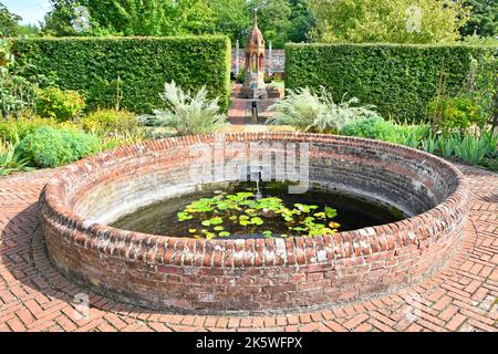 Cressing Temple Tudor Walled Garden runder Pool, der durch eine erhöhte rote Ziegelmauer geschützt und durch eine Rille mit einem kunstvollen Ziegelbrunnen jenseits von Essex UK verbunden ist Stockfoto